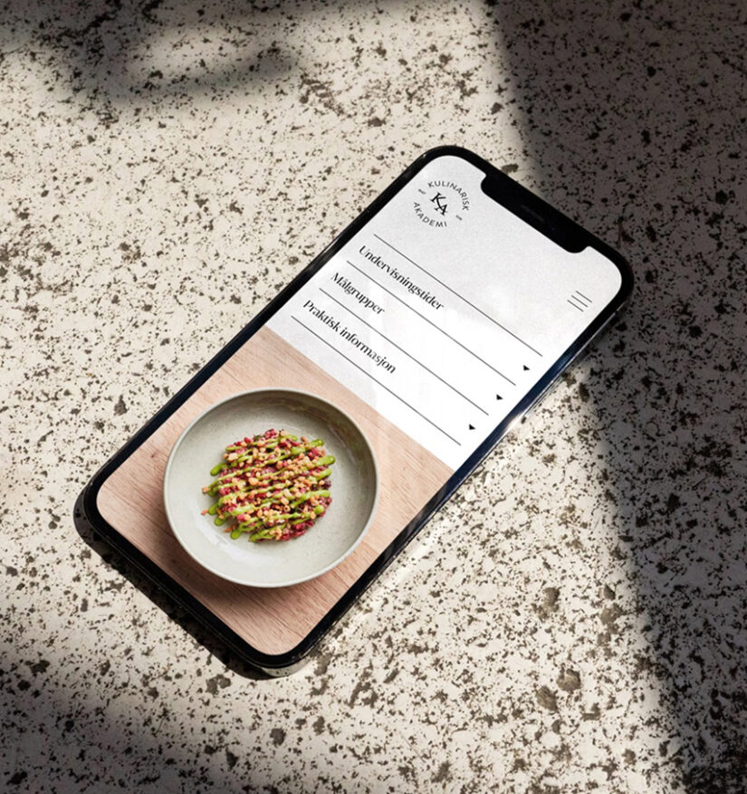 Mobil med Kulinarisk Akademis nettside, som viser menyen og en tallerken med mat