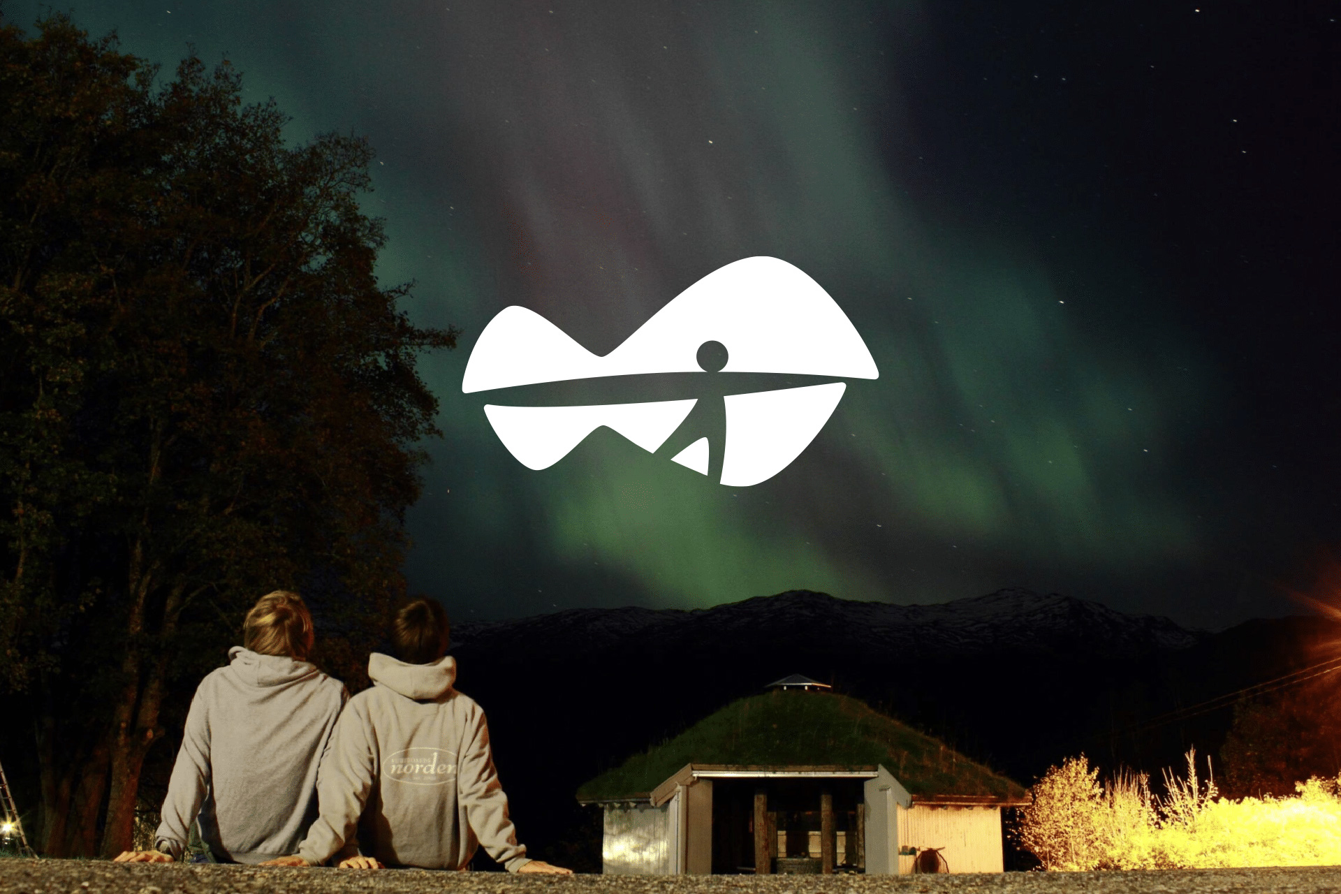 Logoen til Nordfjord folkehøgskule over et bilde av to personer som ser på nordlyset